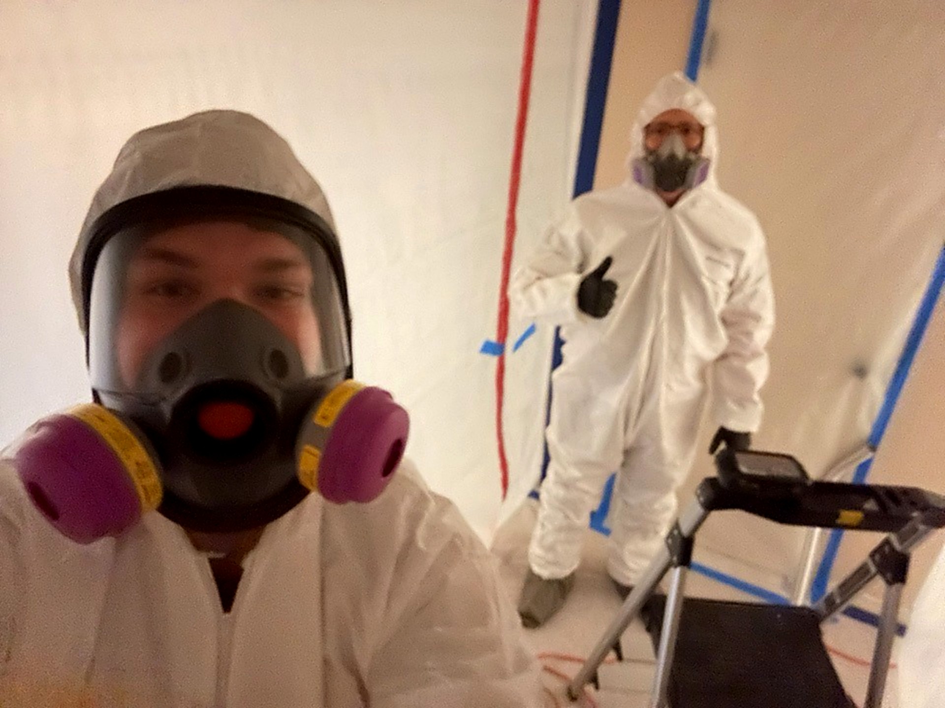 Moisture Pro technicians in full Tyvek PPE and full-face P100 respirators inside IICRC S520 mold containment